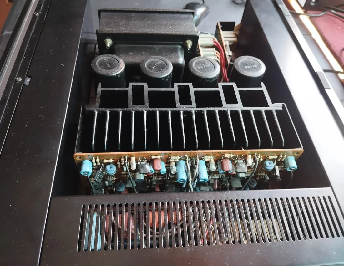 Interior de un amplificador abierto, con disipador, condensadores y placa de componentes
